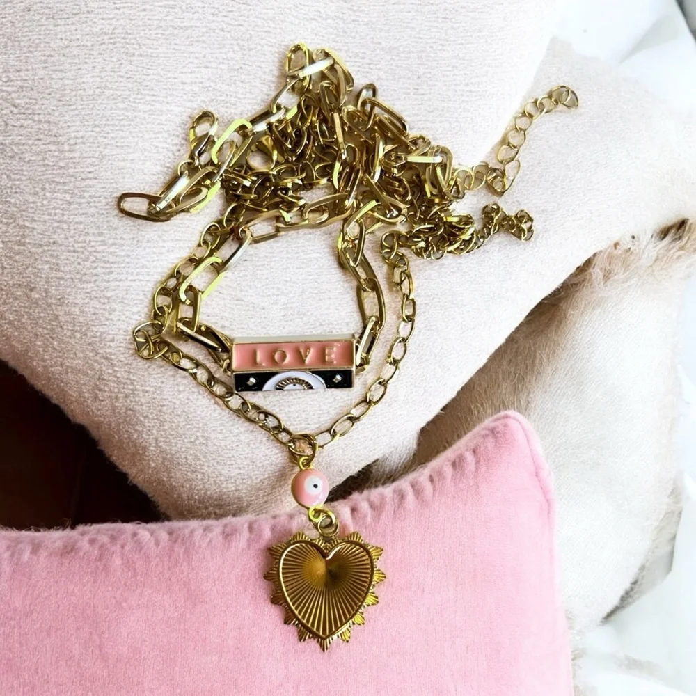 Gold toned chains with black, white, gold, and pastel pink enamel charms.